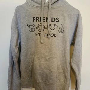 Grå hoodie Friends Not Food  - Grå hoodie från Smart Blanks med trycket 'FRIENDS NOT FOOD' och söta djurmotiv framtill. Tröjan har huva med snörning, magficka. 