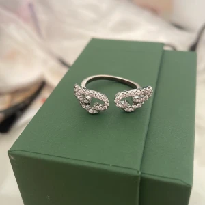 Silverring med glittriga vingar - Superfin silverfärgad ring med två öppna vingar täckta av små glittrande stenar. Ringen har en öppen design som gör den justerbar, från ur&pen