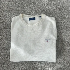 Vit stickad tröja från GANT - Vit stickad tröja från GANT med rund halsringning och diskret broderad logga på bröstet. Tröjan är i bra skick. Pris kan diskuteras.