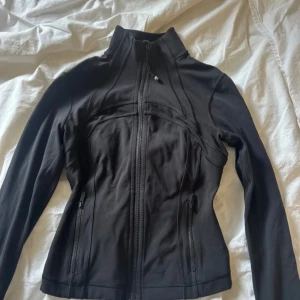 Svart lululemon define jacket - Säljer en svart lululemon define jacket som är i den korta modellen. Jackan är använd ett fåtal gånger och är i superbra skick. Jackan är i st 4 som motsvarar st xs.