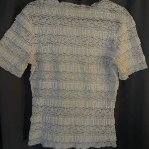 Vit spetsblus med volangdetaljer - Säljer en söt vit blus i spets med korta ärmar och volangdetaljer. Jätte fin och helt slutsåld, säljs för att den inte kommer till användning. Kontakta för egna bilder.