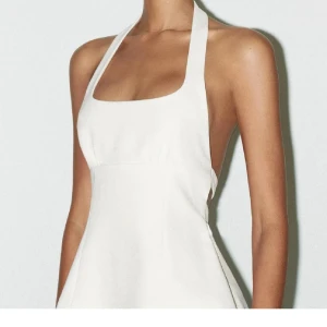 Vit halterneck topp med rosett-detaljer - Lånade bilder från Zaras hemsida!! Säljer en vit halterneck topp med öppen rygg och två snygga rosetter baktill. Toppen har en fyrkantig ringning framtill och är lätt utsvängd nertill. Perfekt för dig som vill ha en stilren och trendig look.