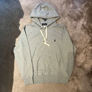 Ralph lauren hoodie - Säljer en helt ny grå Ralph lauren hoodie med sjukt snygg design. Hoodien är i storlek S.