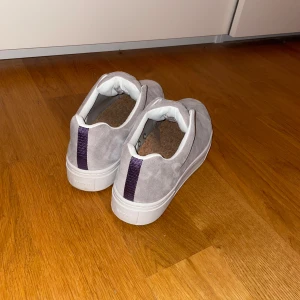 Grå mockasneakers från Eytys - Snygga sneakers från Eytys i ljusgrå mocka med vit sula och diskret lila detalj baktill. Oanvända, säljs pga att dem är för stora för mig 