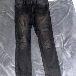 Svarta jeans från East West - Säljer ett par svarta jeans från East West med klassisk femficksdesign och snyggt läderpatch bak i midjan. Jeansen har en rak passform och är tillverkade i mjukt denimtyg. Perfekta till en chill vardagslook. Storlek: 32/32. Slim fit. 