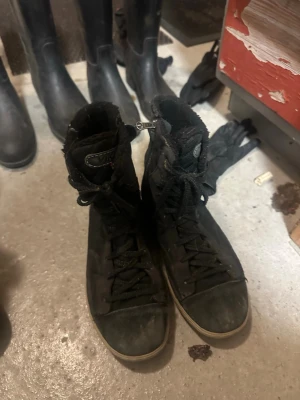 Svarta höga sneakers från Viking - Säljer ett par svarta höga sneakers från Viking i storlek 40. Skorna har snörning, dragkedja på sidan och en platt sula. Insidan är fodrad med mjukt material för extra komfort. Perfekta för dig som gillar streetstyle och vill ha något bekvämt till vardags.