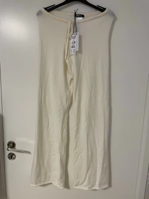 Nya oanvända stickade byxor från Gina Tricot - Nya oanvända Krämvita stickade byxor från Gina Tricot med vida ben och dragsko i midja i storlek S/36.