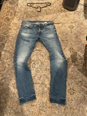 G star blå jeans - Säljer ett par G star  jeans i väldigt nice blå tvätt med snygga slitningar och whiskers. Modellen har normal midja och smal passform hela vägen ner. Femficksmodell med knappgylf. Perfekta till sneakers och hoodie. Tror storleken är typ 32 hittar ingen lapp men fråga om mått om ni vill.