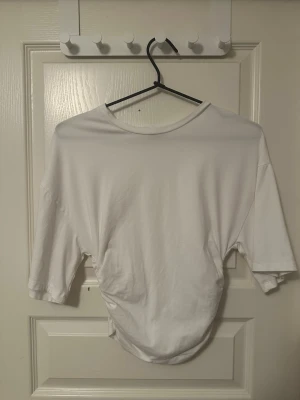 Vit croppad topp från Gina Tricot - Säljer en vit topp i mycket bra skick från Gina Tricot i mjuk bomull. Toppen är kortärmad och cool snörningsdetalj i sidan som ger en snygg twist. Perfekt till jeans! Priset kan förhandlas!