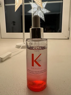 Kérastase Genesis serum - Genesis Anti Hair-Fall Fortifying Serum från Kérastase i en genomskinlig glasflaska med röd botten och silverfärgad pipett. Innehåller 90 ml och är berikad med amineksil, ingefärsrot och koffein. Perfekt för dig som vill boosta håret.