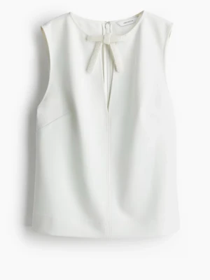 Festtopp - Säljer en vit ärmlös topp från H&M Edition🌟Toppen har en rund halsringning och en dekorativ rosett framtill täckt av små pärlor. Använd ett fåtal gånger🤍🤗 