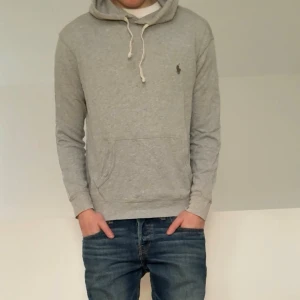 Grå Ralph Lauren Hoodie - Säljer en sjukt fet grå hoodie från Ralph Lauren. Tröjan är i strl S och sitter som S. Tröjan är även i bra skick förutom lite slitning/dragning vid snörets ingång som ni kan se på bild 5. Hör gärna av er vid frågor elr funderingar!!        