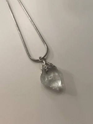 Kristall halsband  - Bilderna visar ett halsband med en silverfärgad kedja och en klar bergskristall som hänge. Kristallen är äkta. Helt oanvänd och går att byta kedja! 🫶