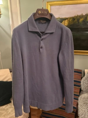 Loro Piana Baby Cashmere tröja  - Exklusiv blå pikétröja från Loro Piana i 100% baby cashmere. Tröjan har klassisk krage, tre knappar framtill och långa ärmar. Supermjuk och lyxig känsla, perfekt för dig som gillar stilrena och bekväma plagg. 13.5 microns lägsta på marknaden (det bästa). Kostar 1700€ från Loro Pianas hemsida. Storlek 50 passar mer som en 48 så S/M. Innerlappen är half av men det är inget som påverkar helhetsintrycket. Det finns även en lätt doft av parfym som försvinner med lite tid. 