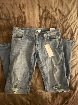 Gina tricot young 14+ Sparkle low flare jeans ljusblå  - Ljusblå jeans med låg midja och flare-ben. Snygga slitningar framtill och broderade detaljer på bakfickorna. Jeansen har klassisk femficksdesign och är gjorda i mjukt denimtyg. Perfekta för dig som gillar en avslappnad men ändå trendig look.