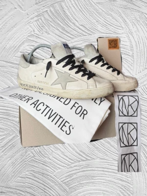 Golden Goose Superstar - Extremt snygga golden goose i storlek 42 som tyvärr är för små för mig, köpta på NK för några månader sedan för över 5 600kr! Kvitto fås såklart med. De har svarta snören på med original fås med. Allt OG som kvitto, box, snören, passport och dustbags fås med.