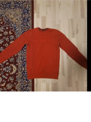 Röd sweatshirt från Sail Racing - Säljer en röd sweatshirt från Sail Racing med broderad logga på bröstet. Tröjan har rund halsringning och långa ärmar. Perfekt för dig som gillar enkel men snygg stil. Materialet känns mjukt och bekvämt.