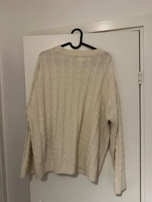 Beige kabelstickad tröja H&M XL - Säljer en beige kabelstickad tröja från H&M i storlek XL. Tröjan har en rund halsringning, lång ärm och ett klassiskt flätmönster över hela plagget. Perfekt för dig som gillar en mysig och oversized look.