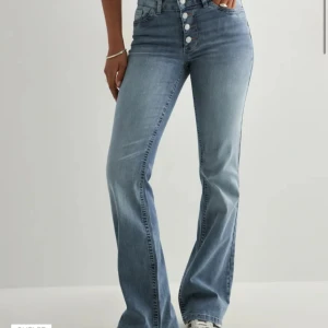 Ljusblå bootcut jeans med knappar - Säljer ett par ljusblå bootcut jeans. Mid waist. Köpte från Nelly storlek 40 = liten L/stor M. Använd endast en gång!!