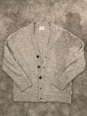 Grå Cardigan - Shit snygg stickad cardigan gjord av lamm ull! Storlek L men sitter lite mer som M, suveränt bra skick, köp för endast 299!