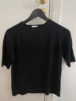 Svart kortärmad topp från H&M XS - En enkel svart topp från H&M i storlek XS. Modellen har rund halsringning och korta ärmar. Materialet är mjukt och lätt, perfekt för lager på lager eller att bära som den är. Passar till allt och är ett måste i garderoben.