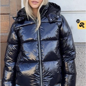 Svart glansig pufferjacka med huva - Säljer en svart, glansig pufferjacka med huva och dragkedja framtill. Köpt från nelly. Sällan använd. Bra kvalitet. 