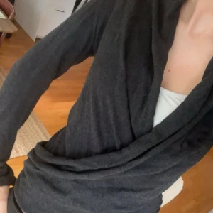 Mörkgrå omlottkofta - Säljer en mörkgrå omlottkofta med långa ärmar och snygg omlottdesign framtill. Koftan har en smickrande passform och är tillverkad i ett mjukt och stretchigt material som känns skönt mot huden. Perfekt att slänga på sig över ett linne eller t-shirt.