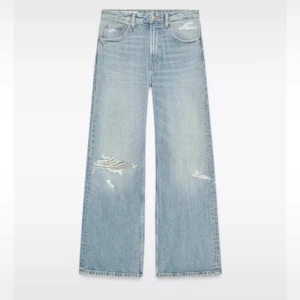Ljusblåa baggy jeans med slitningar - HELT SLUTSÅLDA PÅ ZARA!!! Säljer ett par ljusblå baggy jeans och snygga slitningar på både fram- och baksida. Jeansen har klassisk femficksdesign och är tillverkade i jeansmaterial. Perfekta för en avslappnad och trendig look.