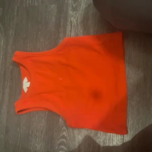 Ribbad röd croppad linnetopp - Snygg croppad linnetopp i starkt röd färg. Toppen är ribbad och ärmlös med klassisk rund halsringning. Perfekt för varma dagar eller som lager under skjorta. Enkel och stilren design som passar till mycket.