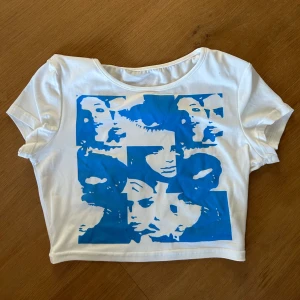 Vit croppad topp med blått tryck - Snygg vit croppad topp med ett stort blått grafiskt tryck av ansikten på framsidan. 