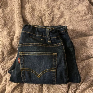Levi's 512 Slim Taper jeans mörkblå - Mörkblå Levi's 512 Slim Taper jeans med klassiska gula sömmar och femficksdesign. Jeansen har en smal passform som smalnar av vid ankeln och är tillverkade i slitstarkt denim. Perfekta för dig som gillar en clean och modern look.