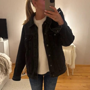 Svart jeansjacka från Bershka - Säljer en svart jeansjacka från Bershka i regular fit. Jackan har klassisk design med knappar framtill, två bröstfickor med lock och långa ärmar. Perfekt oversized känsla och passar till allt. Materialet är denim och färgen är riktigt mörk svart.