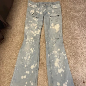 Ljusblå bootcut jeans med blekta fläckar - Säljer ett par ljusblå bootcut jeans med coola detaljer! Lågmidjade och supersnygga. Köptes från vinted men säljer vidare då de inte passade❤️