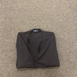 Svart kofta från Blue Harbour - Klassisk svart kofta från Blue Harbour, Marks & Spencer. Tunn och mjuk med lång ärm, v-ringning och knäppning framtill med flera knappar. Perfekt att slänga över en t-shirt eller skjorta. Enkel och stilren design som funkar året runt.