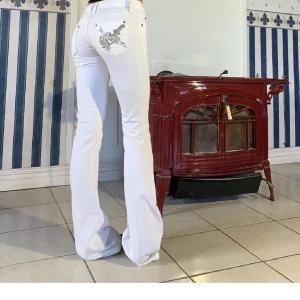 Vita bootcut jeans från Richmond - Snygga vita jeans från Richmond med bootcut passform. Byxorna har broderad detalj med svärd och hjärta på bakfickan samt små nitar.  med klassisk femficksdesign och låg midja. Perfekta för dig som vill sticka ut med coola detaljer.❤️❤️