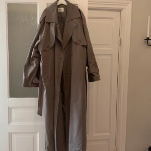 Trenchcoat från Na kd - Denna långa trenchcoat är perfekt nu till hösten, den är i storlek 32 men jackan är oversized. Den är så gott som ny och är väl omhändertagen😊lånade bilder!