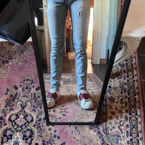 Ljusblå slim jeans med slitningar från Ralph lauren - Säljer ett par ljusblå skinny jeans med slitna detaljer och lätt tvättad look. Jeansen har klassisk femficksdesign och smal passform hela vägen ner. Perfekta för dig som gillar en modern och avslappnad stil. Modellen är 178cm 70kg midja 36cm längd 92cm (18)