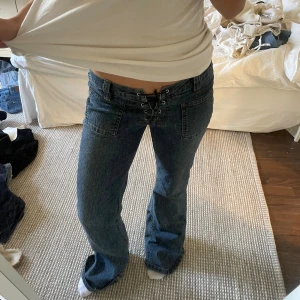 Blå bootcut jeans med snörning - Säljer ett par blå jeans från Jokays med bootcut-modell och låg midja. Midjemåttet är 36 cm (tvärs över) och innebenslängden är 83 cm 💕