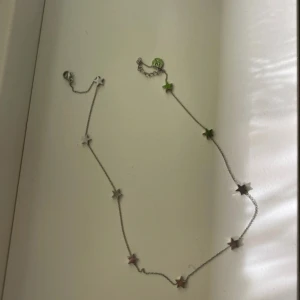 Halsband med stjärnor i silver  - Snyggt halsband med små stjärnor i silver. Kedjan är tunn och smidig, perfekt för att ge din outfit en cool touch. Stjärnorna sitter jämnt fördelade längs hela halsbandet och ger en lekfull men stilren känsla.