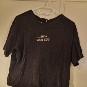 T-shirt - Svart t-shirt från Etirel med vit text på bröstet där det står 'GOOD VIBES ONLY'. Klassisk rund halsringning och korta ärmar. Skön och enkel modell i mjukt bomullsmaterial, perfekt till jeans eller shorts. Lite kortare modell
