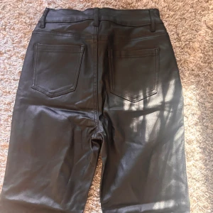 Svarta bootcut byxor i skinnimitation XS - Jag säljer dem här jätte fina byxorna från SHEIN, dom är aldrig använda och köpte dom för mindre än ett halvår sen. Dom är högmidjade och dom är lite för långa för mig i benen och jag är 160 cm lång 💕