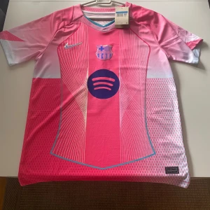 FC Barcelona rosa matchtröja Nike - Snygg FC Barcelona fotbollströja i rosa och lila med Spotify-logga på bröstet och Lamine Yamal 10 på ryggen. Tröjan har korta ärmar, klubbmärke på bröstet och är tillverkad i lätt, ventilerande material. Perfekt för dig som vill sticka ut på planen.