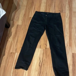Svarta byxor från Polo Ralph Lauren - Snygga svarta byxor från Polo Ralph Lauren i klassisk rak modell. Byxorna har diskreta fickor och stängs med dragkedja och knapp. Perfekta för en stilren look och tillverkade i ett mjukt tyg som känns bekvämt hela dagen.
