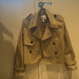 Mörk Beige trenchcoat H&M - Snygg croppad trenchcoat från H&M i mörk beige 😇Säljer då jag har andra jackor som jag hellre använder 💕