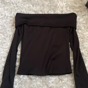 Svart offshoulder topp Pink Woman XS - Säljer en svart offshoulder topp från Pink Woman i storlek XS. Toppen har långa ärmar och en bred kant som man viker ner över axlarna. Perfekt att styla med jeans eller kjol.