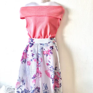  Set topp + blommig kjol - Säljer en vacker vit kjol med blommigt mönster i rosa och blått. Kjolen har en luftig passform och når till knäna. Perfekt för en somrig look!