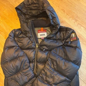 Svart dunjacka från Parajumpers - Säljer en snygg svart dunjacka från Parajumpers i okej skick. Jackan är är i storlek yl(Young large) men den sitter som en S i vuxen storlek. Det är 2  små hål  ermen och även bröstet men Inget man märker till. Vid fler frågor är de bara och skriva