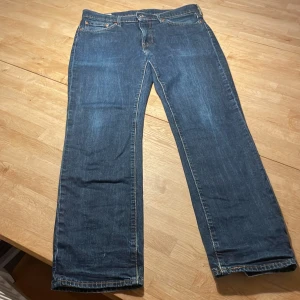 Levi's 514 raka jeans W33 L32 blå - Klassiska blå Levi's 514 jeans med raka ben och normal passform. Jeansen har fem fickor, gylf med dragkedja och är tillverkade i slitstarkt denim. Perfekta för dig som gillar en tidlös look och vill ha ett par jeans som funkar till det mesta.