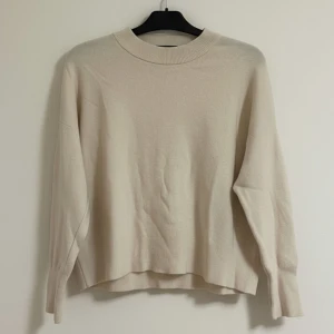 Beige stickad tröja från Vero Moda - Snygg beige stickad tröja från Vero Moda med rund halsringning och långa ärmar. Tröjan har en avslappnad passform och ribbade muddar vid hals, ärmslut och nederkant. 