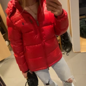 Viral Röd pufferjacka från Polo Ralph Lauren - Säljer en röd pufferjacka från Polo Ralph Lauren med huva och dragkedja framtill. Jackan har en klassisk pufferdesign med broderad logga på bröstet och är perfekt för kyliga dagar. Passar dig som gillar streetstyle och vill sticka ut.